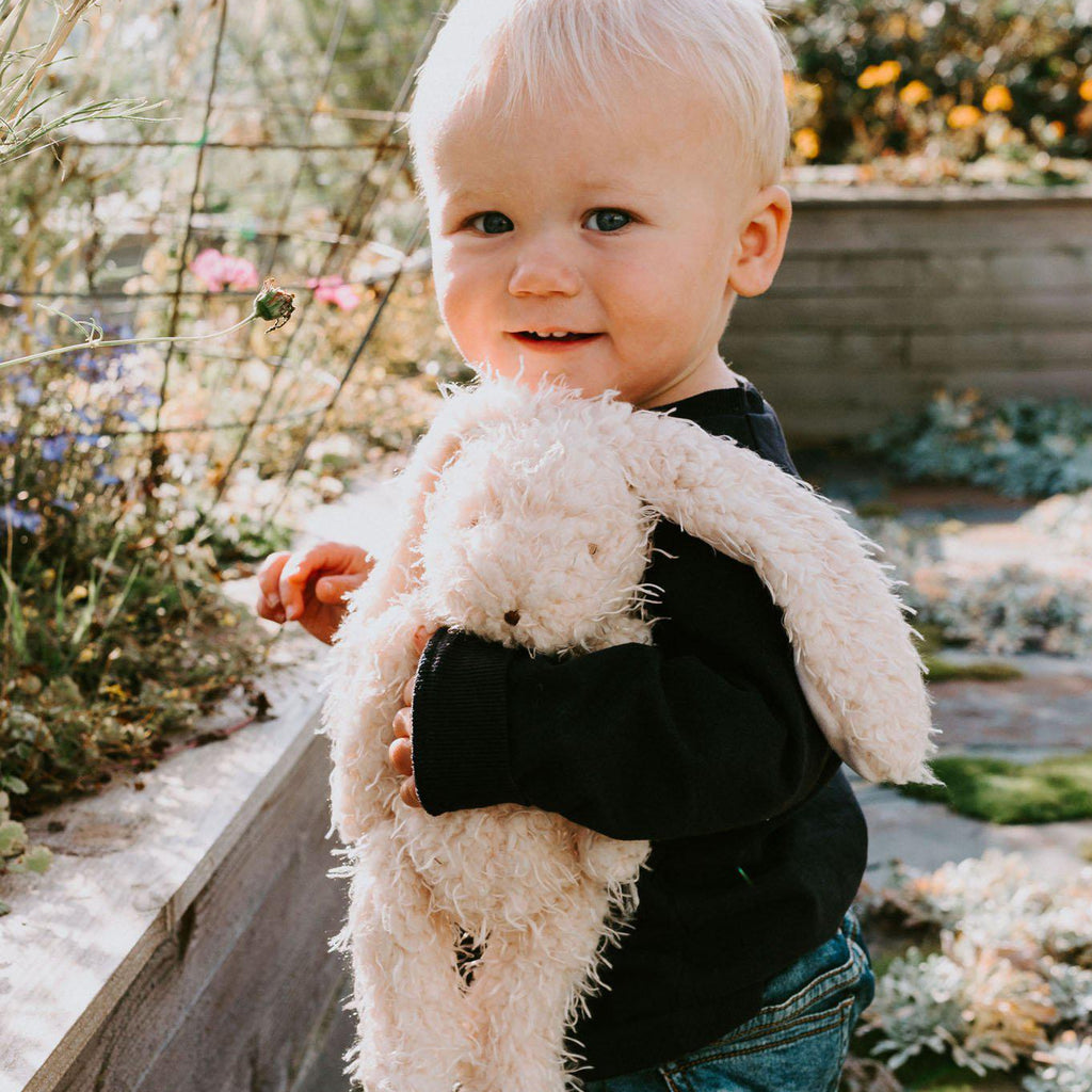 Child holding Harey the Bunny Rabbit plush toy