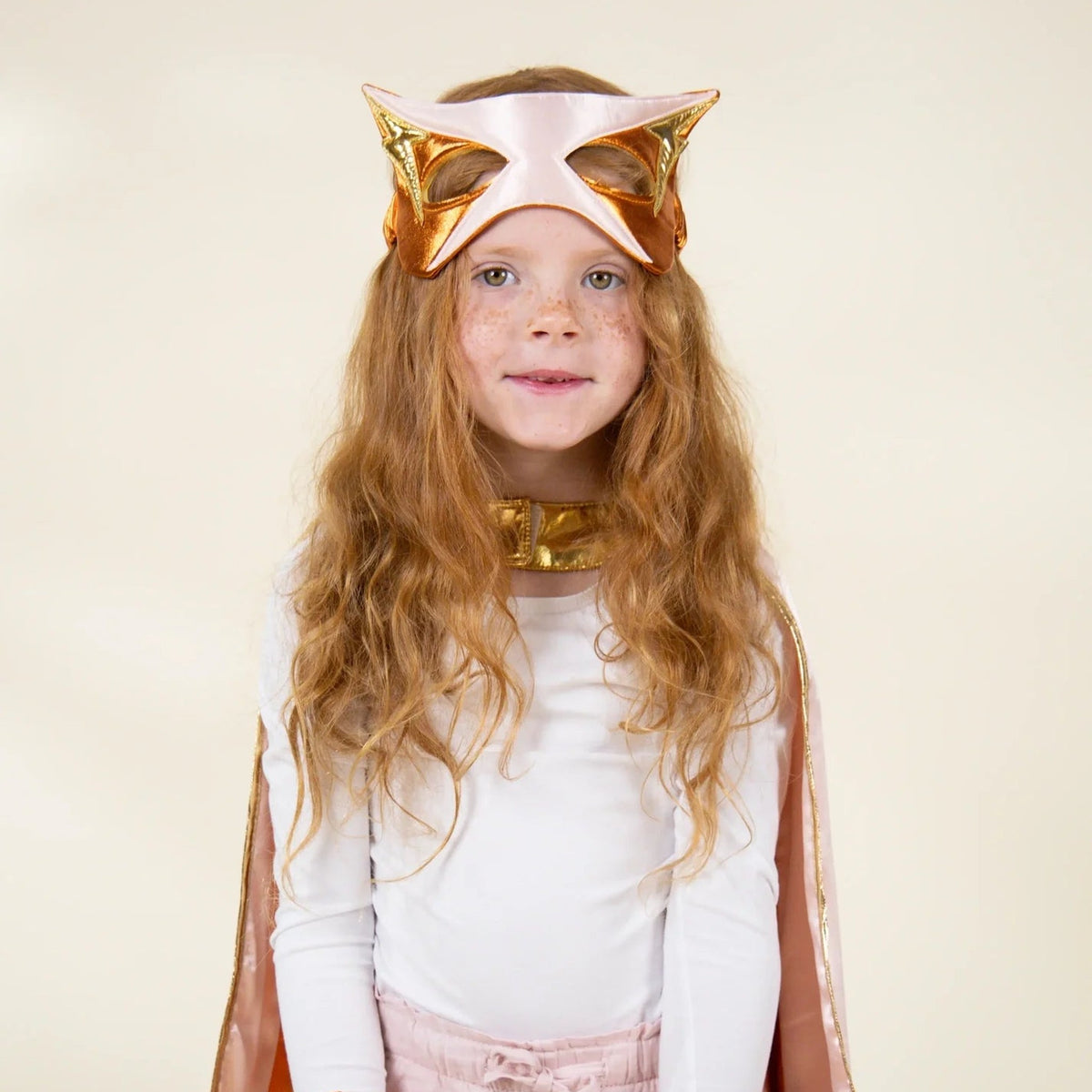 Child wearing coral superhero cape and mask