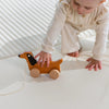 Toddler reaching for wooden dog pull toy
