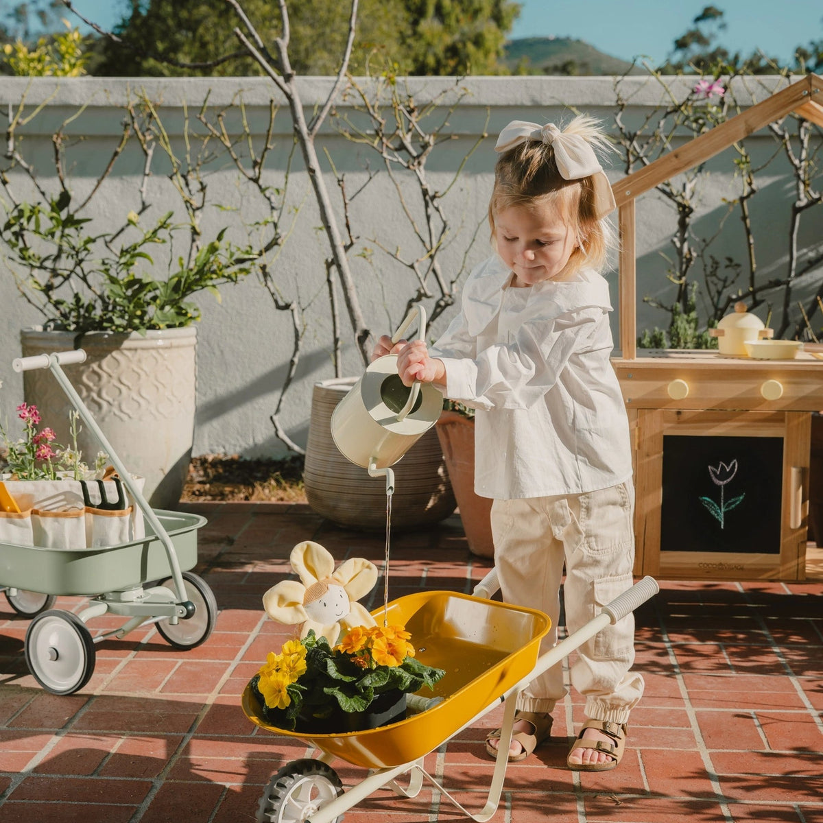 Child gardening with yellow wheelbarrow